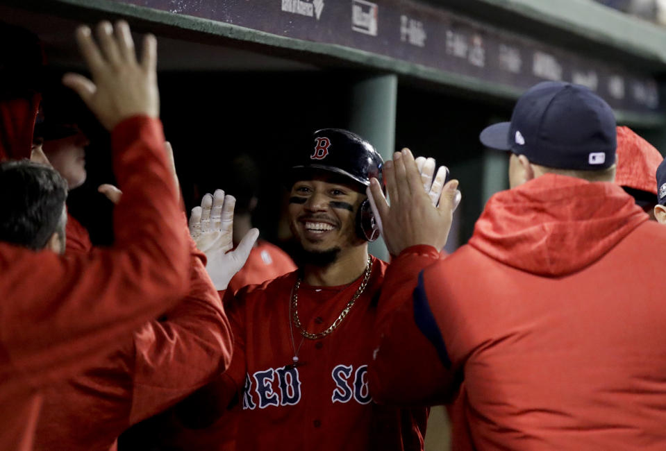 Boston Red Sox's Mookie Betts celebrates in the dugout after scoring of a single by Steve Pearce during the third inning of Game 1 of a baseball American League Division Series against the New York Yankees on Friday, Oct. 5, 2018, in Boston. (AP Photo/Charles Krupa)