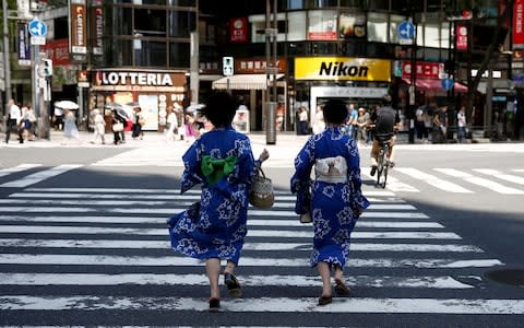  Girls wearing the yukata, or casual summer kimono, run as they cross the road at a shopping district in Tokyo - Credit: Reuters