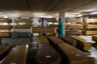 Workers move a coffin with the body of a victim of coronavirus as others coffins are stored waiting for burial or cremation at the Collserola morgue in Barcelona, Spain, April 2, 2020. (AP Photo/Emilio Morenatti)