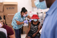 FILE - In this April 10, 2021, file photo, registered nurse Ashleigh Velasco, left, administers the Johnson & Johnson COVID-19 vaccine to Rosemene Lordeus, right, at a clinic held by Healthcare Network in Immokalee, Fla. With coronavirus shots now in the arms of nearly half of American adults, the parts of the U.S. that are excelling and those that are struggling with vaccinations are starting to look like the nation’s political map: deeply divided between red and blue states. (AP Photo/Lynne Sladky, File)