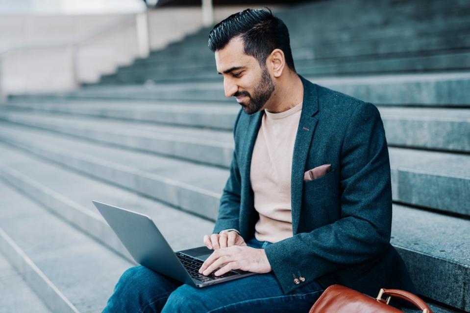 Investor with laptop sitting on steps.