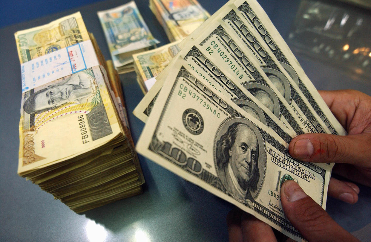 FILE PHOTO: A bank teller counts US dollars beside a pile of Philippine peso in Manila, the Philippines. (Photo: ROMEO GACAD/AFP via Getty Images)