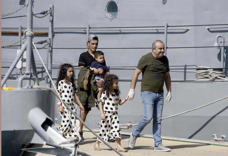 A family is assisted as it disembarks from a Maltese naval vessel in the port of La Valletta in Malta after being transferred from a humanitarian ship which rescued them at sea over a week ago, Sunday, Sept. 30, 2018. The Maltese government said Sunday that the migrants would be then transferred in the coming days to the four countries agreeing to accept them: France, Germany, Spain and Portugal. (AP Photo/Jonathan Borg)