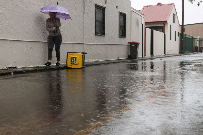 FILE PHOTO: A pedestrian walks along a flooded street as heavy rains affect Sydney, Australia