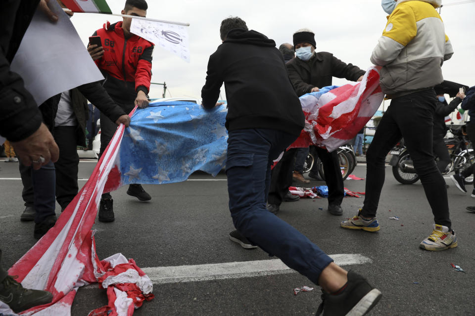 Demonstrators tear up representations of the U.S. flag during the annual rally commemorating the anniversary of Iran's 1979 Islamic Revolution in Azadi (freedom) Sq. in Tehran, Iran, Friday, Feb. 11, 2022. Thousands of cars and motorbikes paraded in the celebration, although fewer pedestrians were out for a second straight year due to concerns over the coronavirus pandemic. (AP Photo/Vahid Salemi)