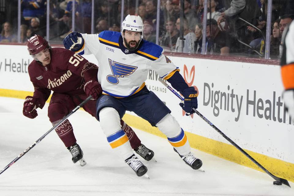 St. Louis Blues defenseman Nick Leddy shields Arizona Coyotes defenseman Sean Durzi (50) from the puck during the first period during an NHL hockey game Wednesday, Nov. 22, 2023, in Tempe, Ariz. (AP Photo/Rick Scuteri)