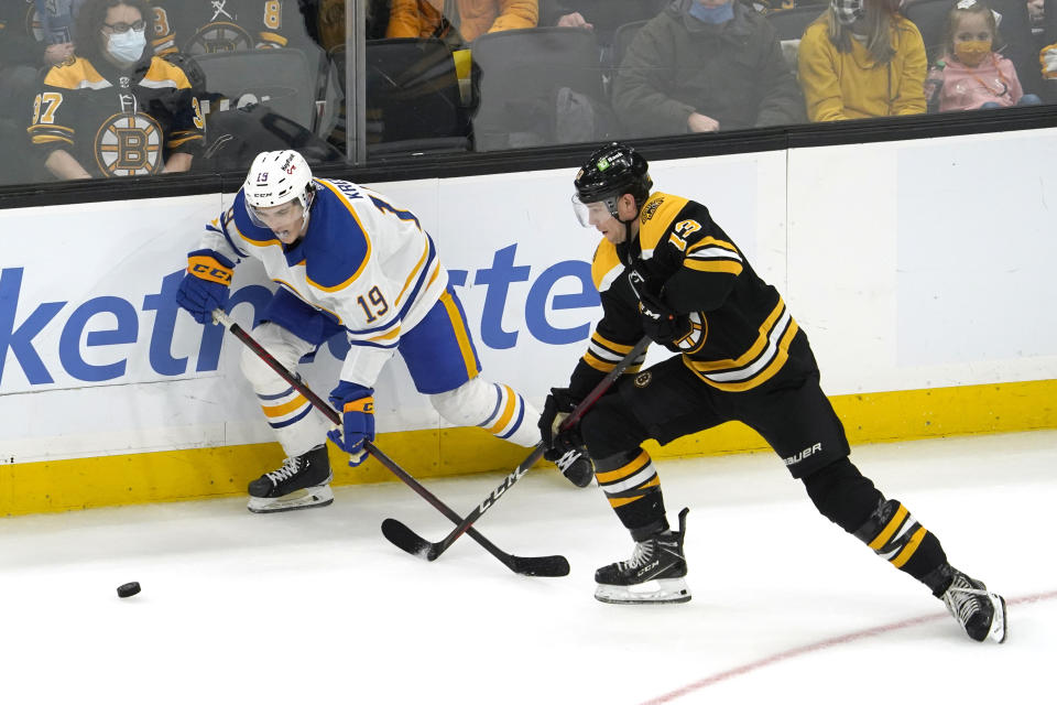 Boston Bruins center Charlie Coyle (13) and Buffalo Sabres center Peyton Krebs (19) compete for the puck during the third period of an NHL hockey game, Saturday, Jan. 1, 2022, in Boston. (AP Photo/Mary Schwalm)