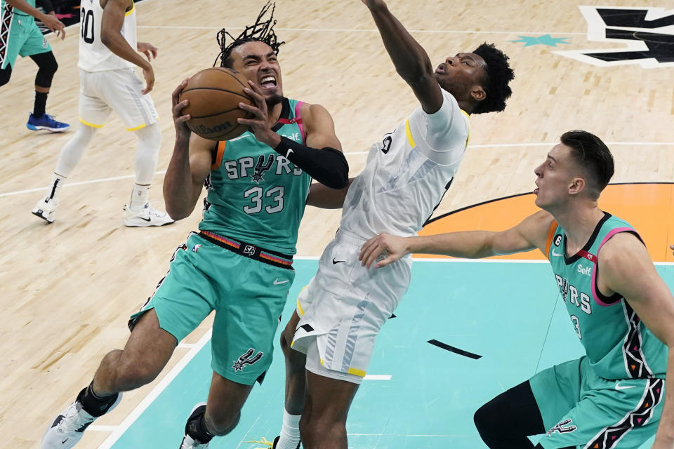 San Antonio Spurs guard Tre Jones (33) drives to the basket against Utah Jazz center Damian Jones, center, during the first half of an NBA basketball game in San Antonio, Wednesday, March 29, 2023. (AP Photo/Eric Gay)