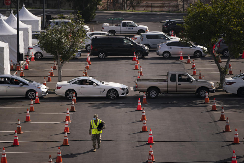 A National Guardsman walks across a federally-run COVID-19 vaccination site as motorists wait to get their vaccine on the campus of California State University of Los Angeles in Los Angeles, Calif., Tuesday, Feb. 16, 2021. (AP Photo/Jae C. Hong)