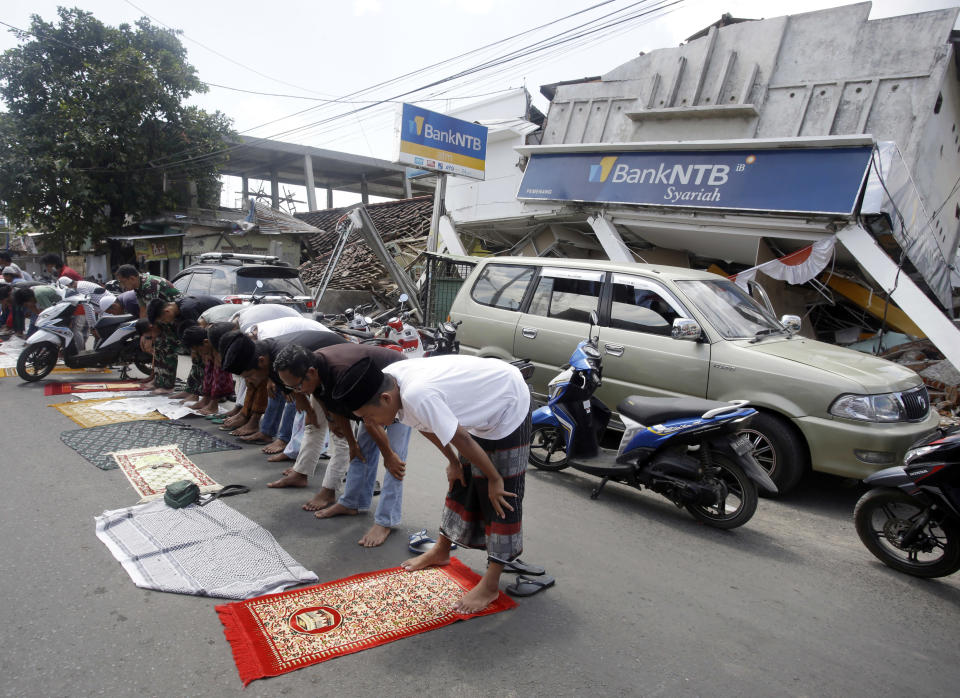 <p>Villagers attend Muslim Friday prayers as damaged buildings by an earthquake are seen in the background in North Lombok, Indonesia, Friday, Aug. 10, 2018. (Photo: Firdia Lisnawati/AP) </p>