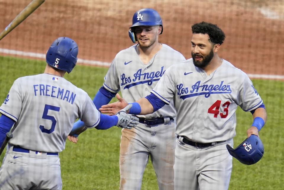 Edwin Rios (43) and Gavin Lux are greeted by Freddie Freeman as they return to the dugout after scoring.