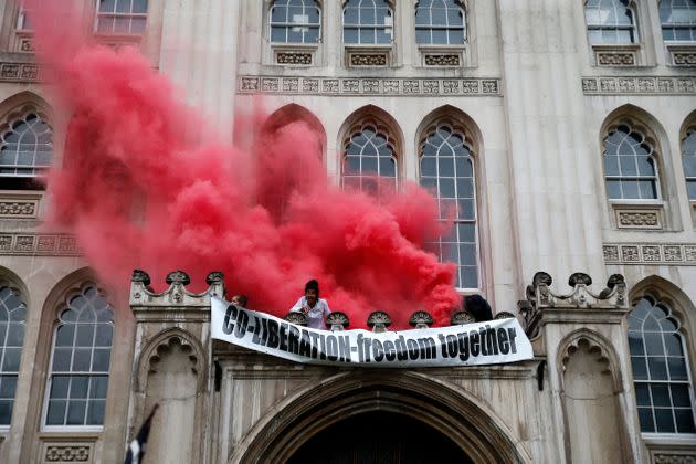 Protesters from Extinction Rebellion light a flare and unfurl a banner from the Guildhall on August 22, 2021 in London, England (Photo: Hollie Adams via Getty Images)