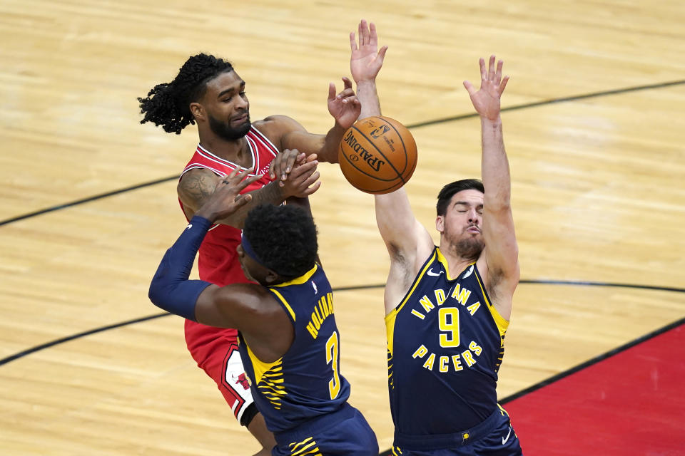 Chicago Bulls' Coby White loses control of the ball under pressure from Indiana Pacers' Aaron Holiday (3) and T.J. McConnell during the first half of an NBA basketball game Saturday, Dec. 26, 2020, in Chicago. (AP Photo/Charles Rex Arbogast)