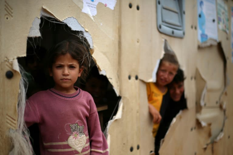 Unos niños desplazados se asoman por los agujeros de su colegio de campaña en un campamento en la localidad siria de Haranabush el 11 de mayo de 2024 (Aaref Watad)