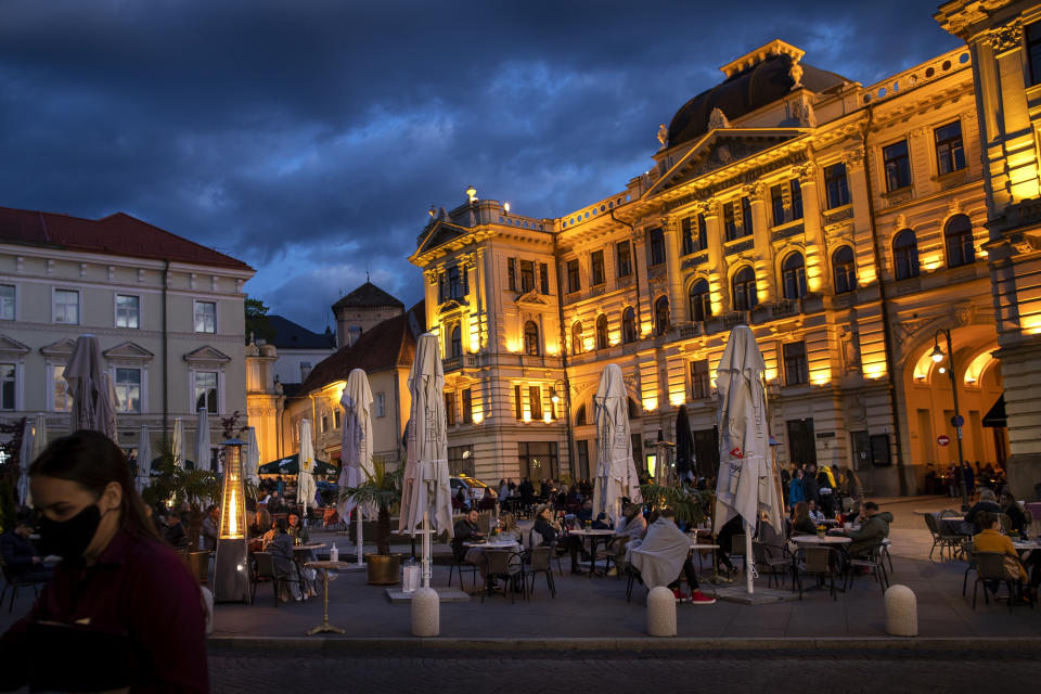 People sit outside a bar in Vilnius, Lithuania, Friday, May 22, 2020. The Lithuanian government extended the nationwide coronavirus quarantine until May 31, but gave the green light for museums, libraries, cafes, restaurants, hairdressers and beauty salons, and retail stores in shopping malls to reopen. (AP Photo/Mindaugas Kulbis)