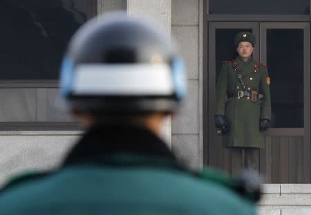 A North Korean (R) and a South Korean soldier face each other at the Panmunjom truce village in the demilitarized zone (DMZ) separating the two Koreas in Paju, about 50 km north of Seoul, December 28, 2011. REUTERS/Kim Kyung-Hoon/Files