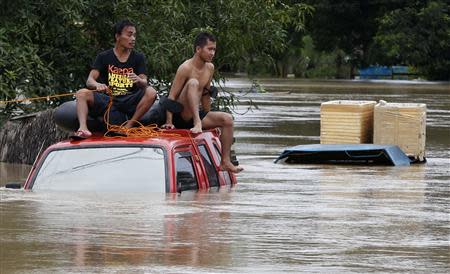 Residents sit on the roof of a vehicle submerged in heavy flooding brought by tropical depression "Agaton", in Butuan on the southern Philippine island of Mindanao January 21, 2014. REUTERS/Erik De Castro