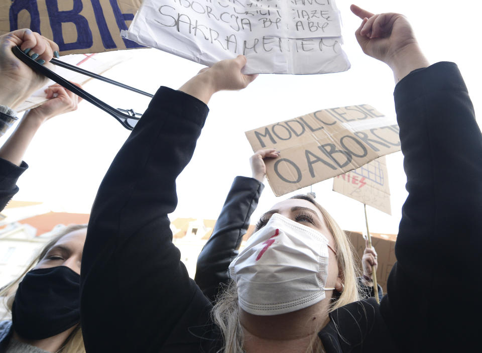 Demonstrators wear protective face masks during a protest a church where they were protesting church support for tightening Poland's already restrictive abortion law in Warsaw, Poland, Sunday, Oct. 25, 2020. Poland constitutional court issued a ruling on Thursday that further restricts abortion rights in Poland, triggering four straight days of protests across Poland.(AP Photo/Czarek Sokolowski)