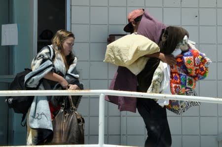 Evacuees leave a fire station with their belongings after an earthquake near Trona