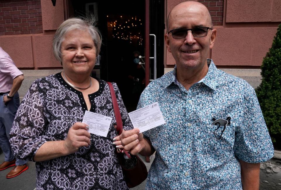 two restaurant-goers hold up their CDC vaccine cards. proof of vaccination is mandatory for indoor dining in New York City now.