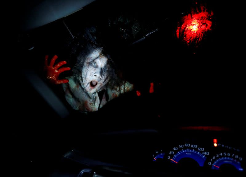 An actor dressed as a zombie performs during a drive-in haunted house show, performed by Kowagarasetai, for people inside a car in order to maintain social distancing amid the spread of the coronavirus disease (COVID-19), in Tokyo