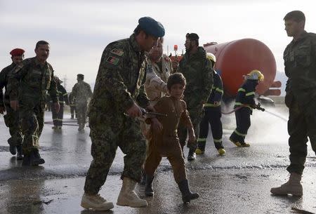 An Afghan National Army officer escorts a slightly injured boy from the site of a suicide attack on the outskirts of Mazar-i-Sharif, Afghanistan February 8, 2016. REUTERS/ Anil Usyan