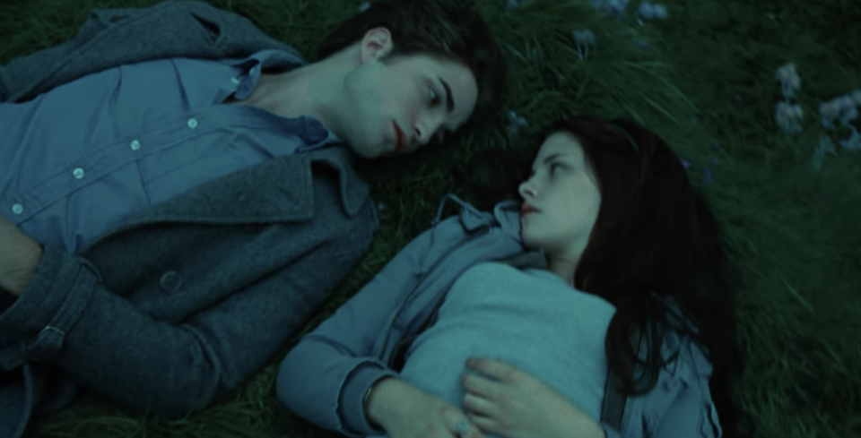 Bella and Edward lying on the ground on their backs side-by-side and looking at each other