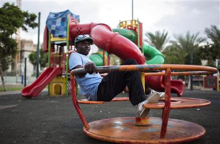 An African migrant sits on a ride at a playground in south Tel Aviv July 17, 2013. REUTERS/Amir Cohen