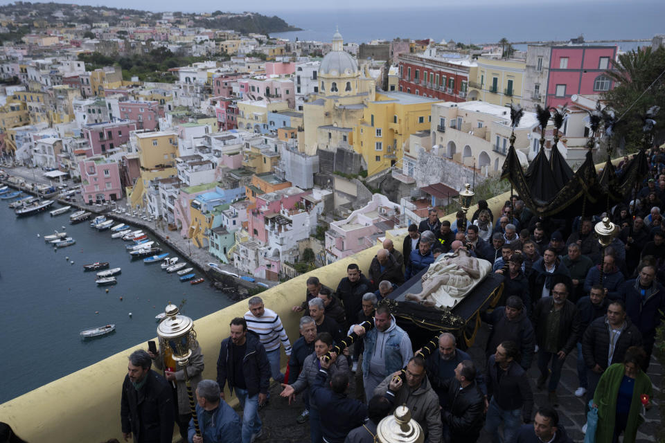 Faithful carry an 18th century wooden Christ before the start of a procession the in Procida Island, Italy, early Friday, March 29, 2024. Italy is known for the religious processions that take over towns big and small when Catholic feast days are celebrated throughout the year. But even in a country where public displays of popular piety are a centuries-old tradition, Procida's Holy Week commemorations stand out. (AP Photo/Alessandra Tarantino)