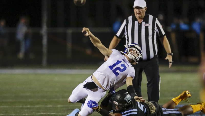 Dallen Martinez (12) of the Bingham Miners throws the ball while being tacked by Dimitri Lovio (5) of the West Jordan Jaguars in West Jordan on Friday, Oct. 7, 2022. The Miners won 48-0.
