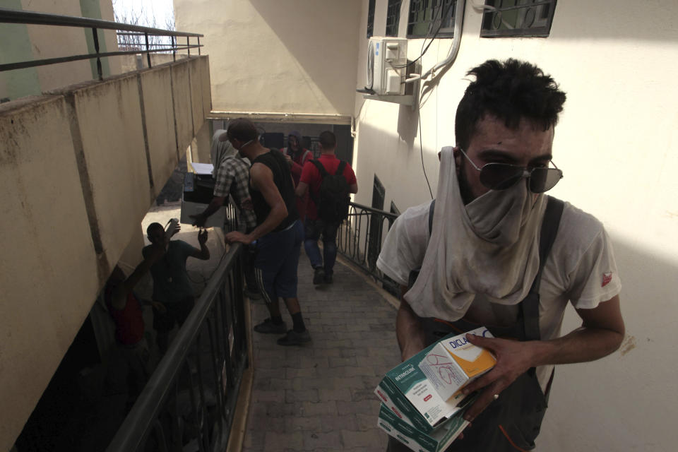 A man saves drugs in a small hospital as residents evacuate a village near Tizi Ouzou some 100 km (62 miles) east of Algiers following wildfires in this mountainous region, Tuesday, Aug.10, 2021. Firefighters were battling a rash of fires in northern Algeria that have killed at least six people in the mountainous Kabyle region, the interior minister said Tuesday, accusing "criminal hands" for some of the blazes. (AP Photo/Fateh Guidoum)