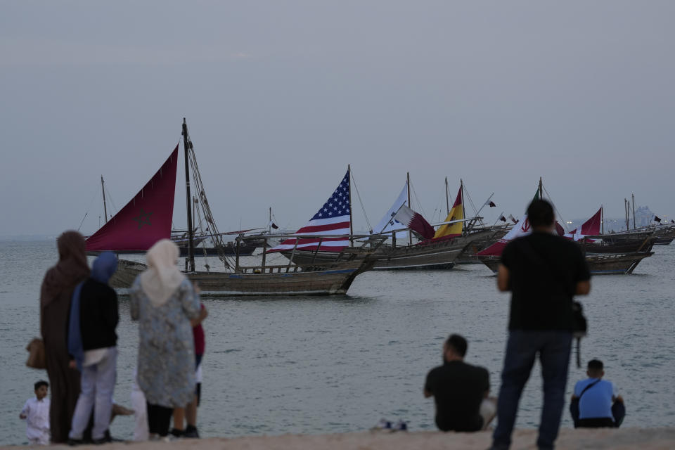 Visitors look at boats carrying the flags of teams participating in the World Cup at Katara Beach during soccer tournament, in Doha, Qatar, Thursday, Dec. 1, 2022. (AP Photo/Lee Jin-man)