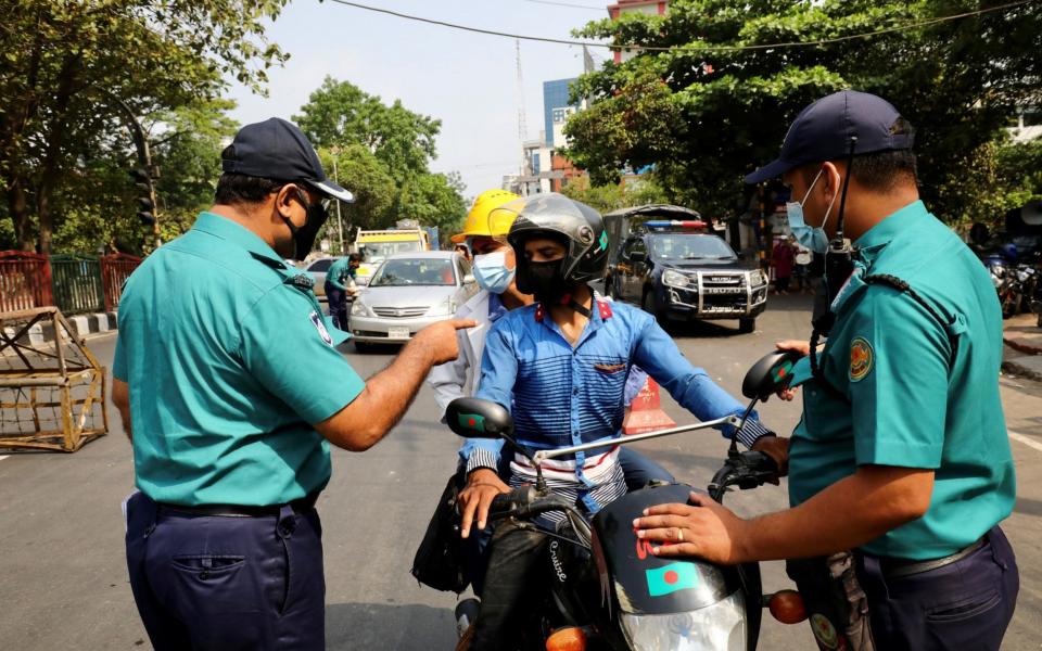 Bangladeshi Policemen stop vehicles as the government imposed restrictions on public movement -  MOHAMMAD PONIR HOSSAIN / REUTERS
