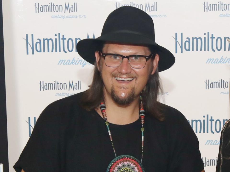 Jay smiling in glasses and a wide hat with a goatee and long hair.