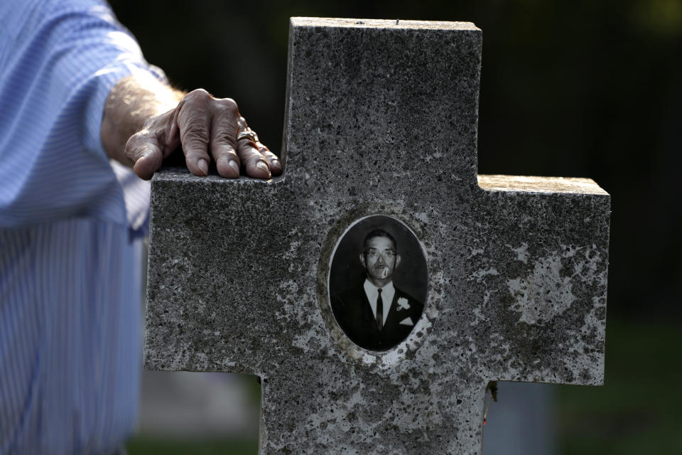 In this Wednesday, May 1, 2019, photo, Oliverio Yarrito, 80, rests his hand against the gravestone of his father, Daniel Yarrito, as he speaks to family members at the Eli Jackson Cemetery in San Juan, Texas. (AP Photo/Eric Gay)