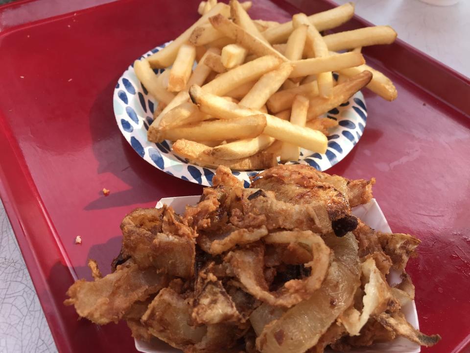 Fries and onion pieces on paper plates on red tray from arctic roadrunner in alaska