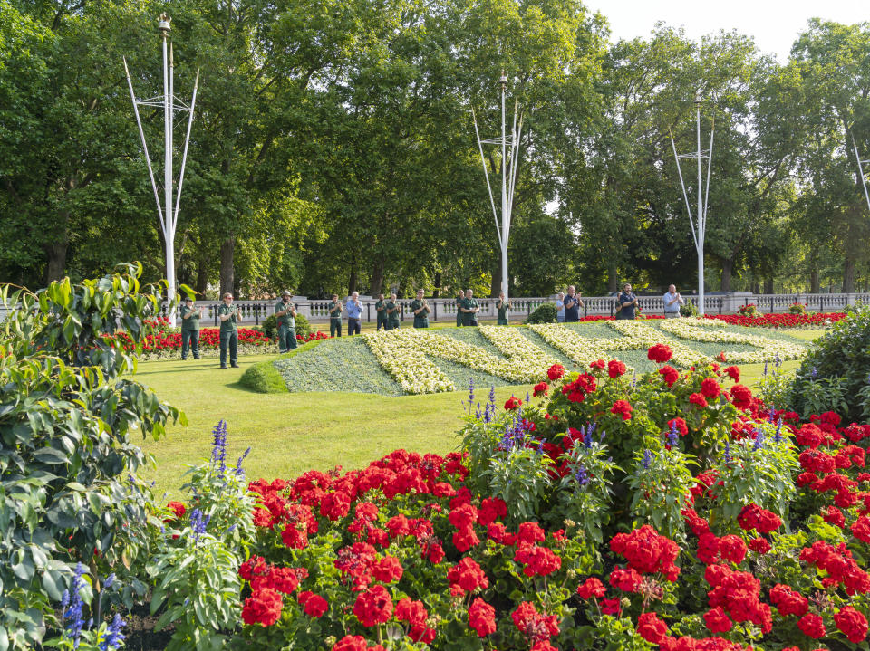 Royal Parks staff applaud the NHS's 72 birthday behind one of two specially created 12 x 5 metre flowerbeds in front of Buckingham Palace in the Memorial Gardens in St James's Park. The letters are made up of 1,500 Begonia semperflorens 'Heaven White' plants in each bed, while the background is 21,000 plants of Echeveria imbricate, Senecio serpens and Sedum pachyclados.