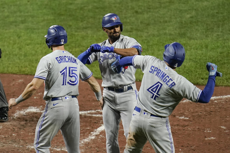 Toronto Blue Jays' Marcus Semien, center, celebrates with Randal Grichuk (15) and George Springer (4) after Semien scored all three of them on a three-run home run off Baltimore Orioles relief pitcher Tanner Scott during the seventh inning of the second game of a baseball doubleheader, Saturday, Sept. 11, 2021, in Baltimore. (AP Photo/Julio Cortez)