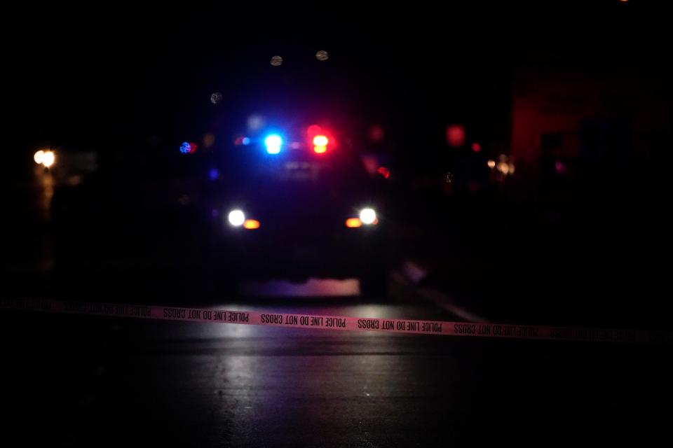 A police vehicle with flashing lights is seen behind police tape following a March 31 shooting at an office building in Orange, California.