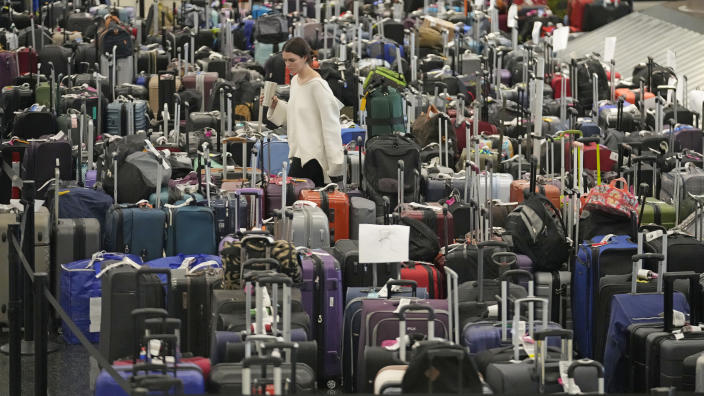 FILE - A woman walks through unclaimed bags at Southwest Airlines baggage claim at Salt Lake City International Airport Thursday, Dec. 29, 2022, in Salt Lake City. With its flights now running on a roughly normal schedule, Southwest Airlines is turning its attention to luring back customers and repairing damage to a reputation for service after canceling 15,000 flights around Christmas. The disruptions started with a winter storm and snowballed when Southwest's ancient crew-scheduling technology failed. (AP Photo/Rick Bowmer, File)