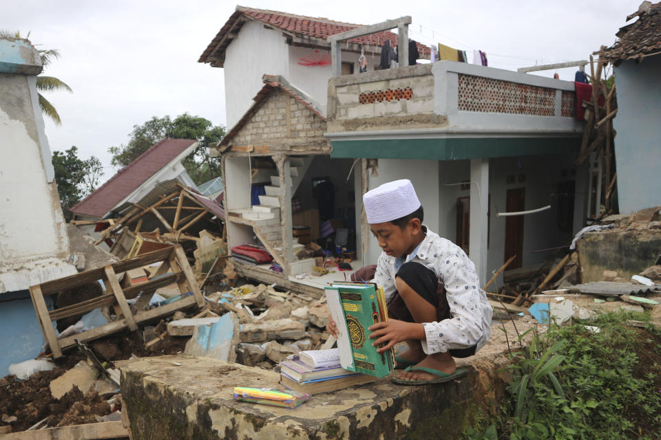 A boy sorts holy book of Quran he salvaged from under the rubble at the ruins of Al Buroq Islamic Boarding School which was badly damaged during Monday's earthquake, in Cianjur, West Java, Indonesia, Wednesday, Nov. 23, 2022. More rescuers and volunteers were deployed Wednesday in devastated areas on Indonesia's main island of Java to search for the dead and missing from an earthquake that killed hundreds of people. (AP Photo/Rangga Firmansyah)