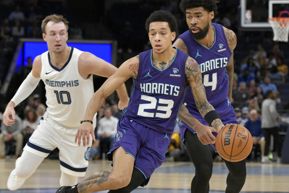 Charlotte Hornets guard Tre Mann (23) dribbles the ball next to center Nick Richards (4) and Memphis Grizzlies guard Luke Kennard (10) during the first half of an NBA basketball game Wednesday, March 13, 2024, in Memphis, Tenn. (AP Photo/Brandon Dill)