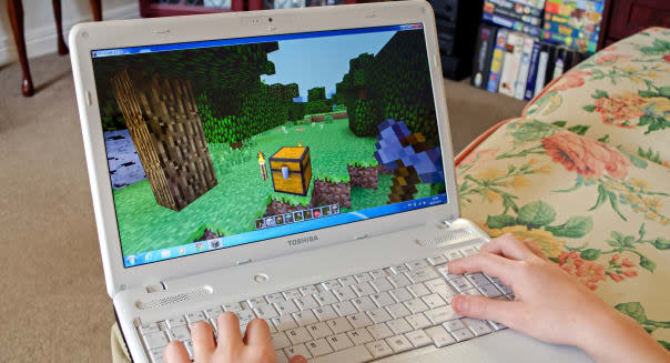 young boy playing minecraft on a laptop computer