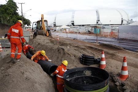 Workers work on areas of infrastructure next to the construction site of the Arena das Dunas stadium, in Natal May 10, 2014. REUTERS/Nuno Guimaraes