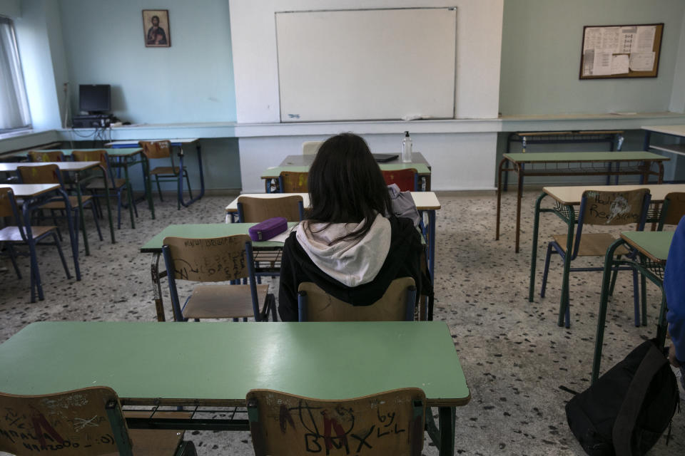 A high school student sits inside a classroom at Glyfada, suburb west of Athens, Monday, April 12, 2021. Home tests have been distributed to teachers and students aged 16-18, as authorities reopened high schools for students in the final three grades on Monday. (AP Photo/Yorgos Karahalis)