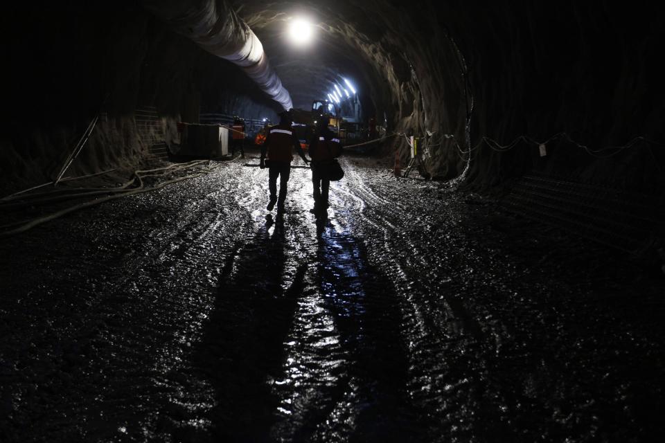 Dos trabajadores caminan por un túnel construido debajo de la mina de cobre de Chuquicamata, en Chile. El auge minero en Chile de principios de siglo XXI atrajo a miles de colombianos al país en busca de trabajo. (AP Photo/Jorge Sáenz)