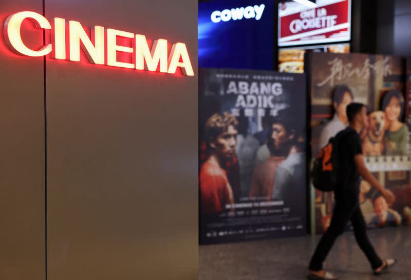 A man passes movie posters at a cinema in Kuala Lumpur