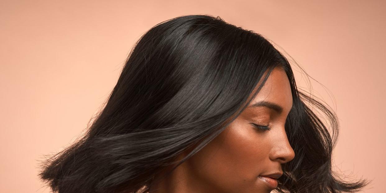 shot of a young attractive woman tossing her hair against a brown background