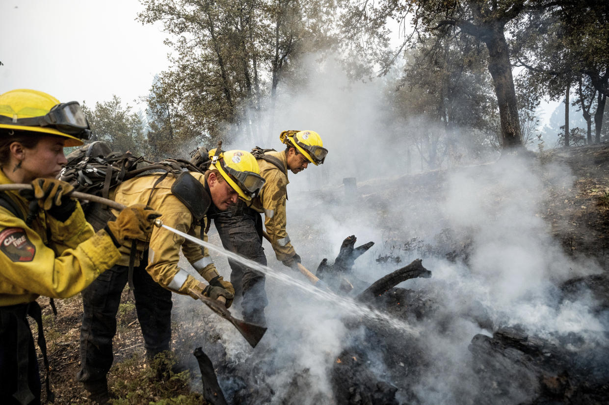 Firefighters mop up hot spots while battling the Oak Fire in the Jerseydale community of Mariposa County, Calif., on Monday, July 25, 2022. From right to left are Sergio Porras, Jerome Alton and Natasha Rodocker. They are part of Task Force Rattlesnake, a program comprised of Cal Fire and California National Guard firefighters. (AP Photo/Noah Berger)
