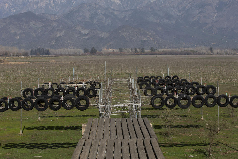 A dock once surrounded by water is seen at an abandoned Aculeo Lagoon resort, in Paine, Chile, Friday, Aug. 23, 2019. Despite having one of the largest fresh water reserves in the world, Chilean authorities declared an agricultural emergency this week as rural areas in the province of Santiago suffer the effects of the worst drought that has hit the area in decades. (AP Photo/Esteban Felix)